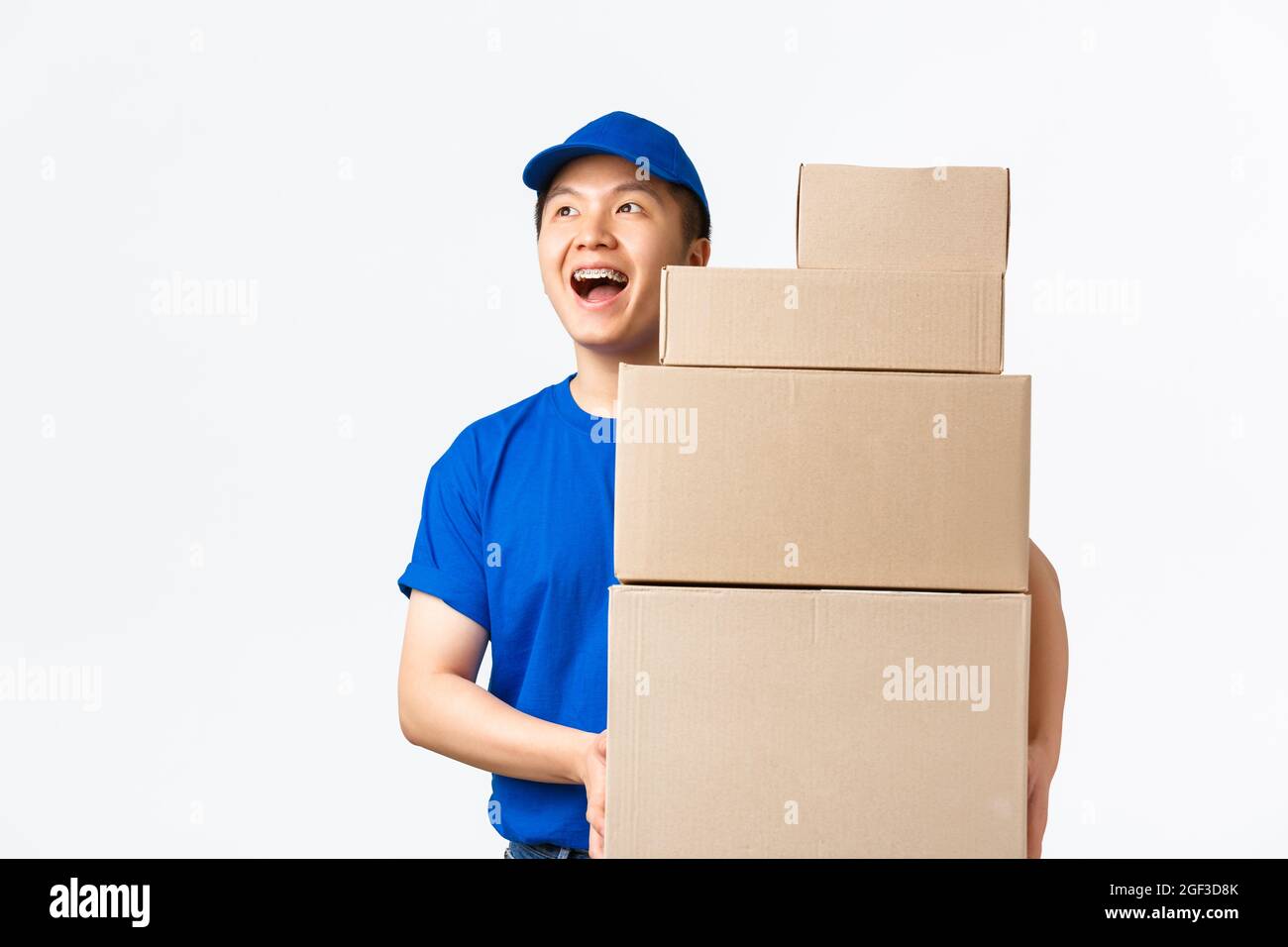 Online shopping, fast shipping concept. Dreamy smiling asian male courier in blue uniform