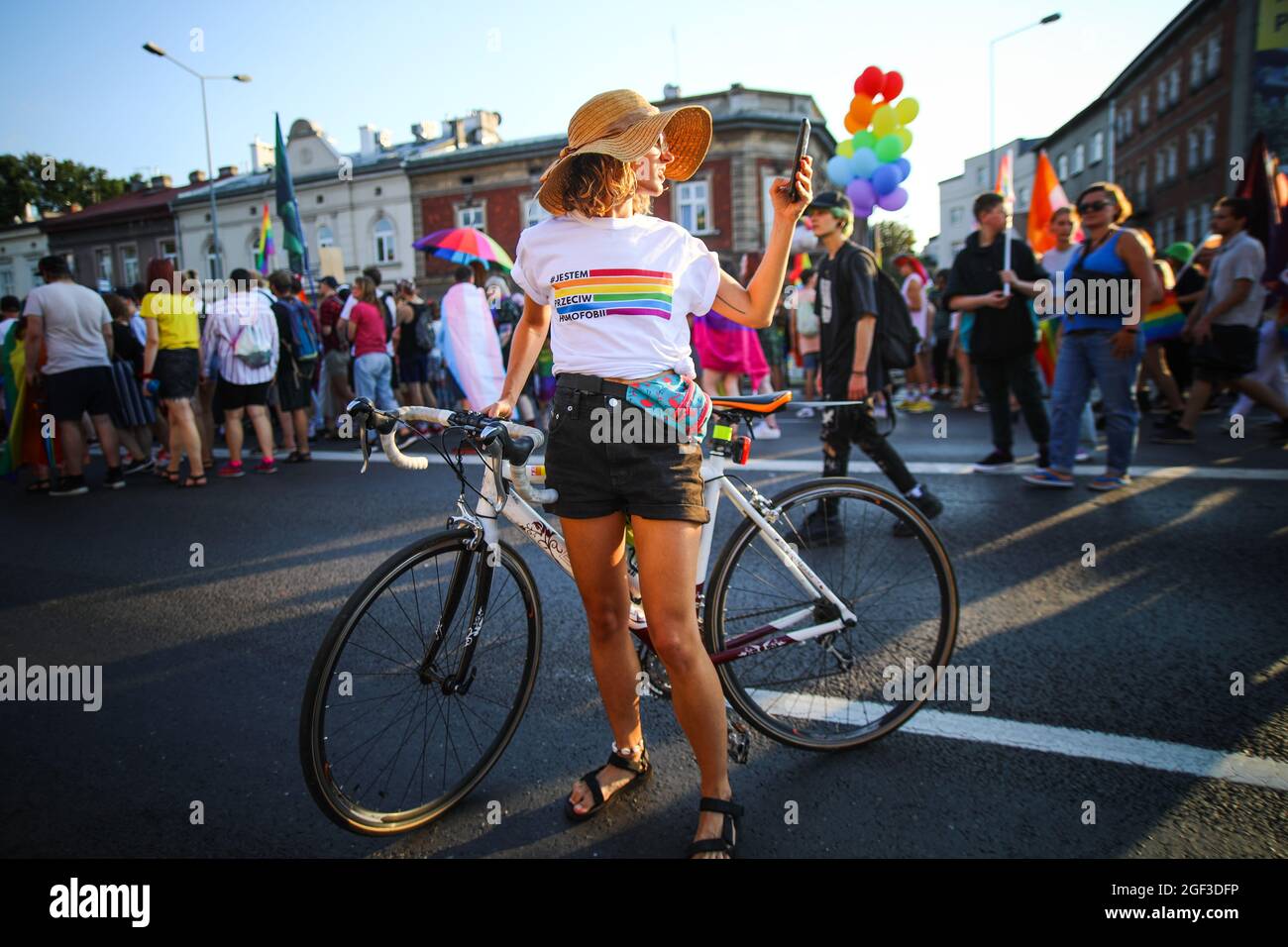 A participant is seen taking a photo with a smartphone while holding a road bike during the march.  Annual Equality March also known as 'Pride Parade' Stock Photo