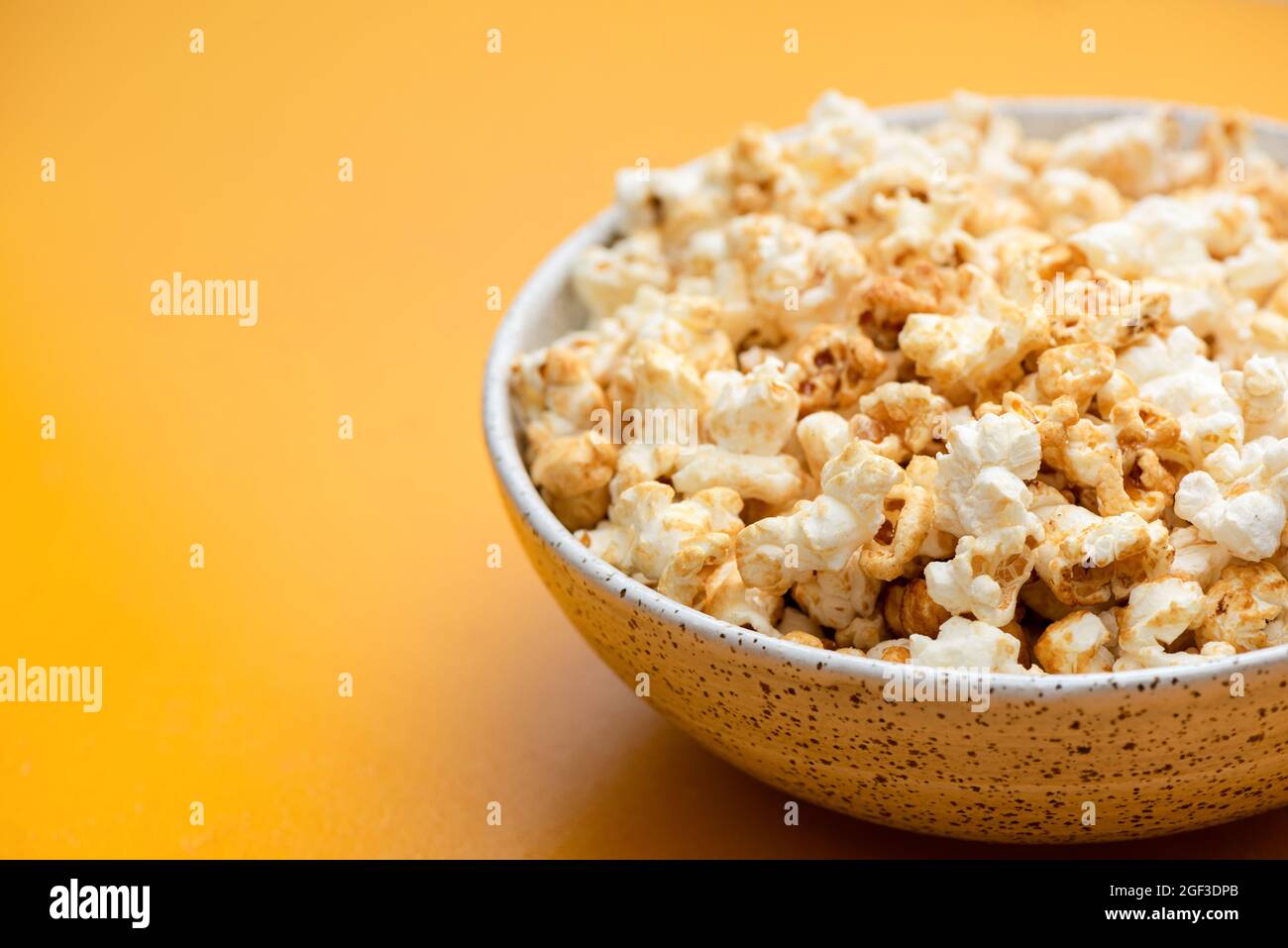 Popcorn in bowl on yellow background isolated. Closeup view, copy space Stock Photo
