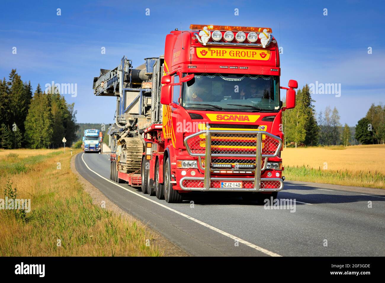 Scania truck of PHP Group hauls crushing and screening equipment as oversize load, another transport follows. Urjala, Finland. August 12, 2021 Stock Photo