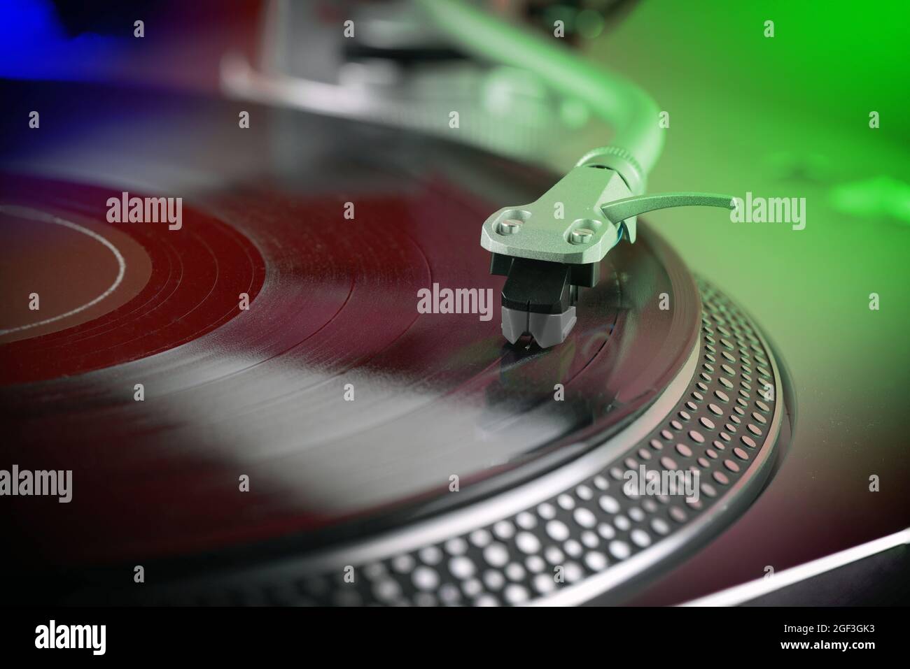 close view of a vinyl record playing  on a turntable, colored  lighting Stock Photo