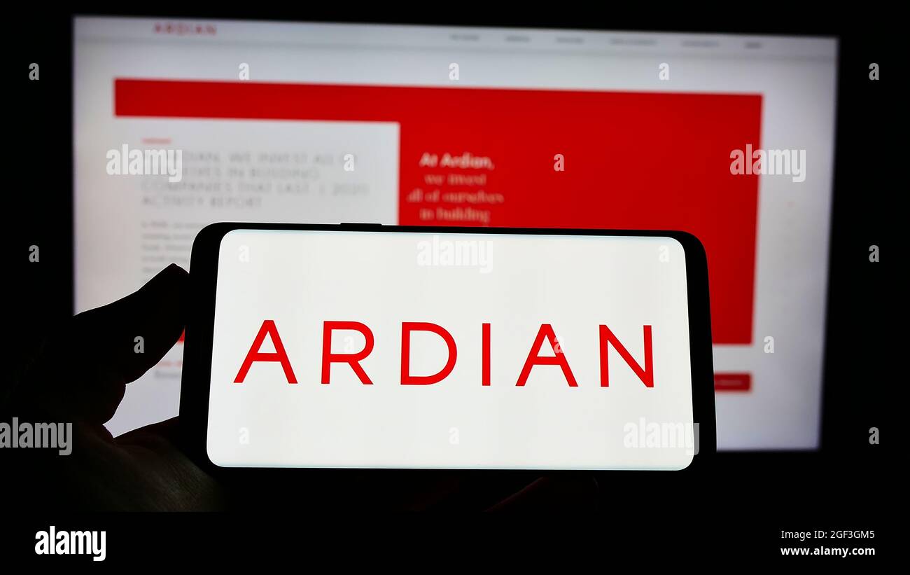 Person holding cellphone with logo of French private equity company Ardian on screen in front of business website. Focus on phone display. Stock Photo