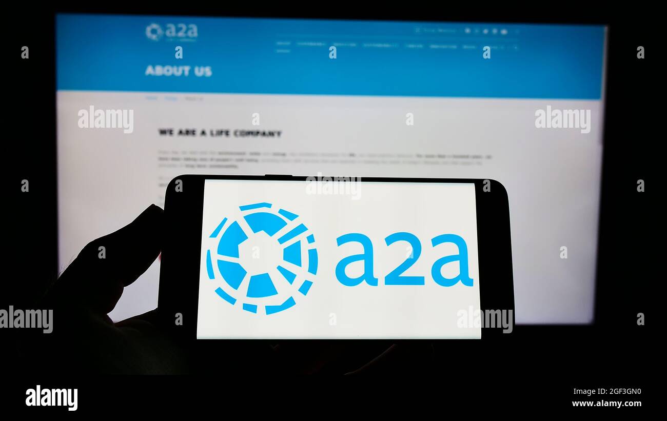 Person holding smartphone with logo of Italian utility company A2A S.p.A. on screen in front of website. Focus on phone display. Stock Photo