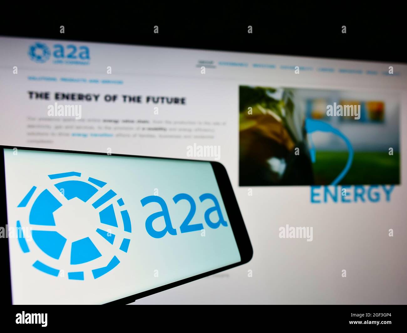 Mobile phone with logo of Italian utility company A2A S.p.A. on screen in front of business website. Focus on center-left of phone display. Stock Photo