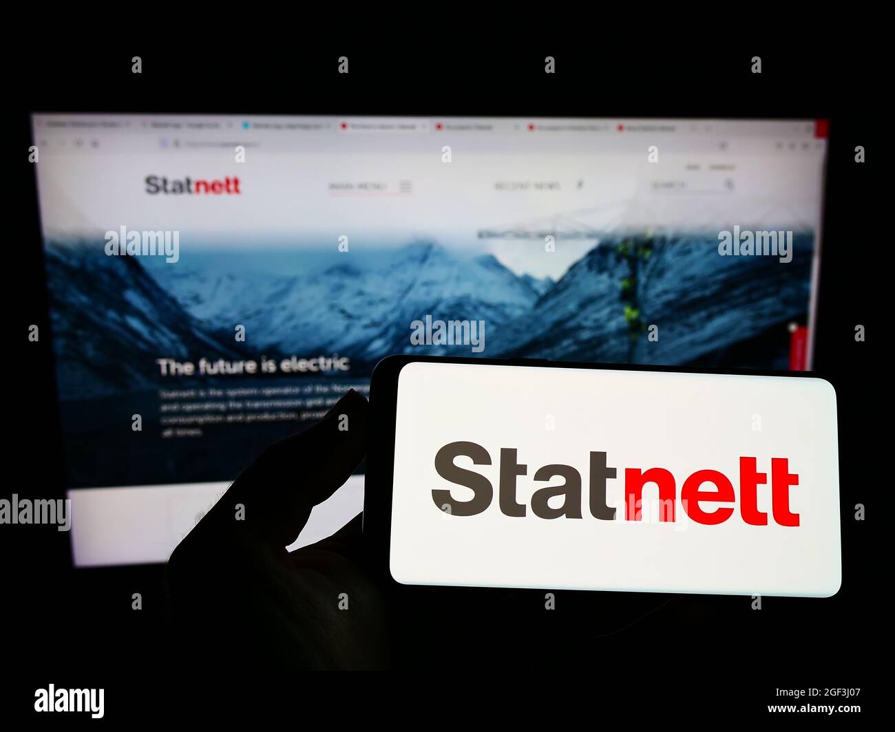 Person holding smartphone with logo of Norwegian electricity company Statnett SF on screen in front of website. Focus on phone display. Stock Photo