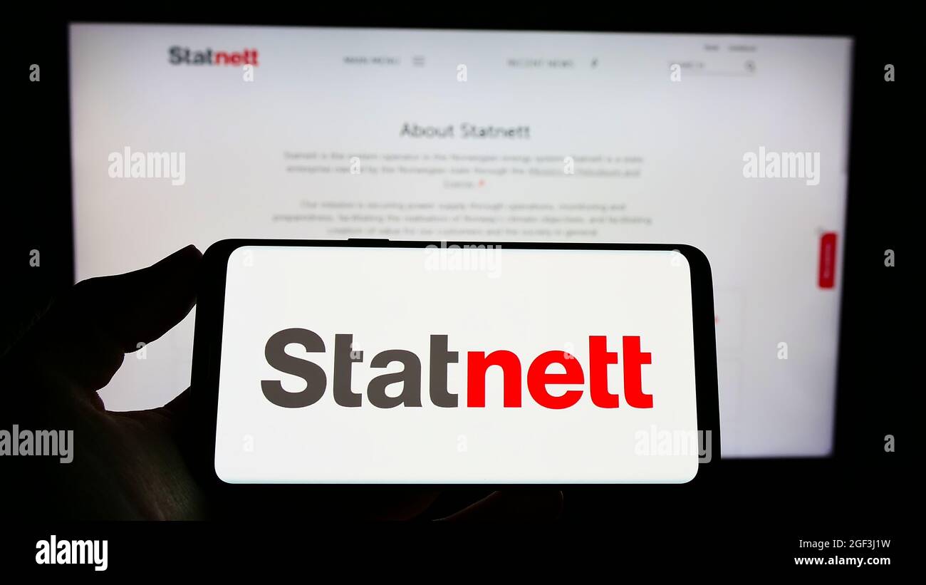 Person holding cellphone with logo of Norwegian electricity company Statnett SF on screen in front of business webpage. Focus on phone display. Stock Photo