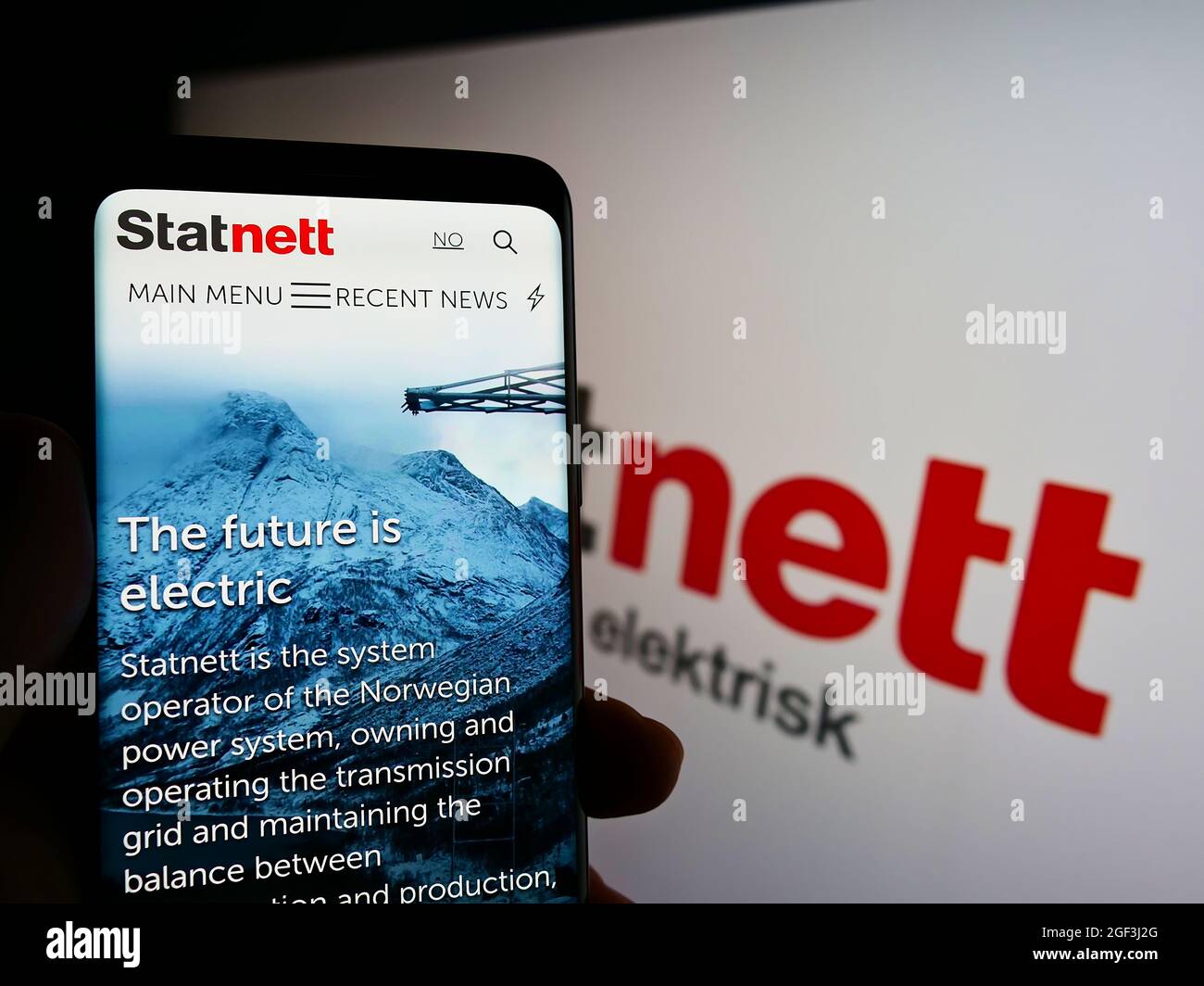Person holding smartphone with website of Norwegian electricity company Statnett SF on screen in front of logo. Focus on center of phone display. Stock Photo
