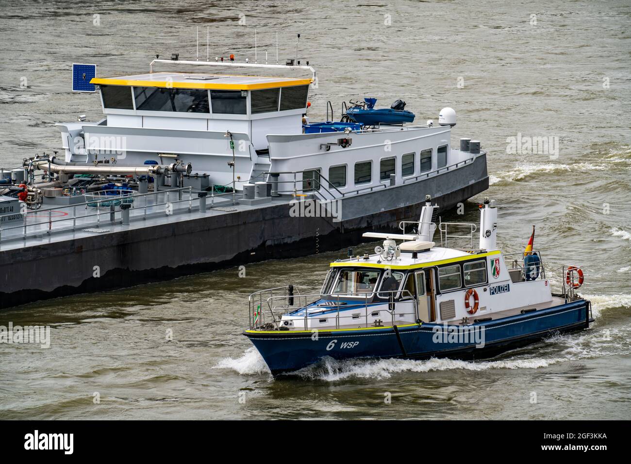 Boat of the water police, on the Rhine, next to a cargo ship, Cologne