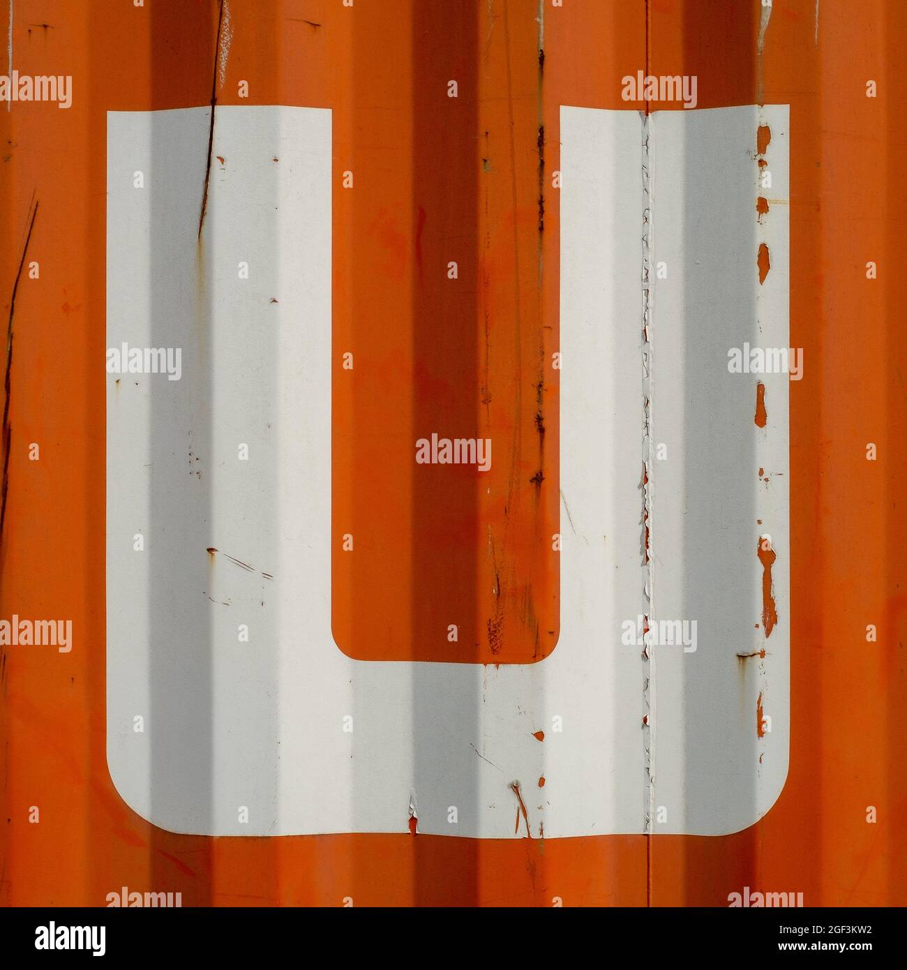 Grunge single letter U on an orange corrugated enameled metal background Stock Photo