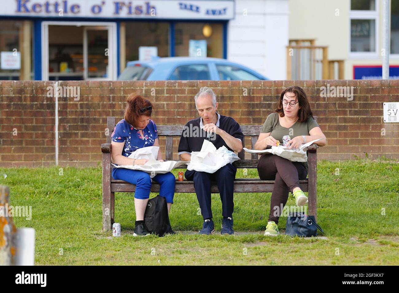 Rye, East Sussex, UK. 23 Aug, 2021. UK Weather: Sunny day in the historic town of Rye with visitors enjoying the fine and dry weather. A family sitting on a bench by the quay eating fish and chips. Photo Credit: Paul Lawrenson /Alamy Live News Stock Photo