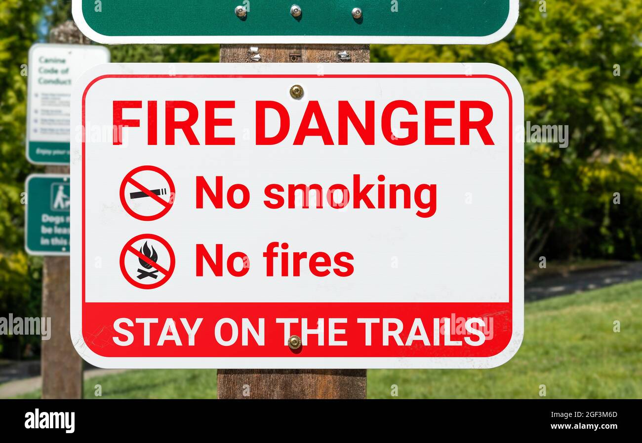 Fire danger sign, outside. Warning poster or information placard placed in parks, trails and nature during extreme heat or drought. No smoking and no Stock Photo