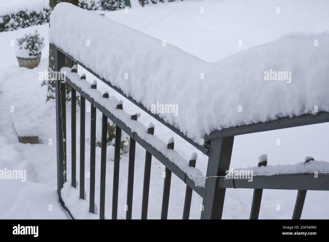 snow covered black metal handrail by the house across snowy backyard. Winter season Stock Photo