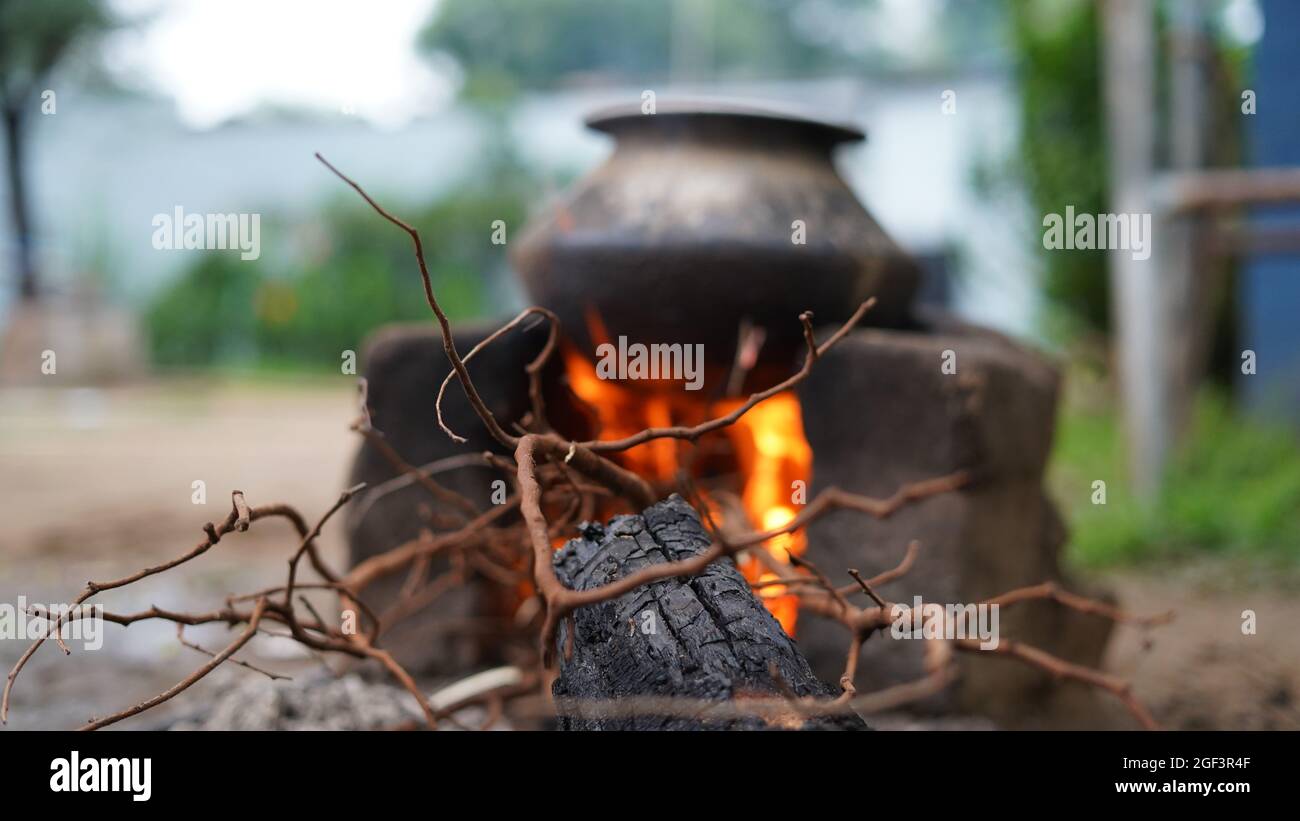 Blurred shot, Outdoor Indian earthen cooking stove Countryside stove or Chulha or clay stove with a black colored circular vessel on it, Stock Photo