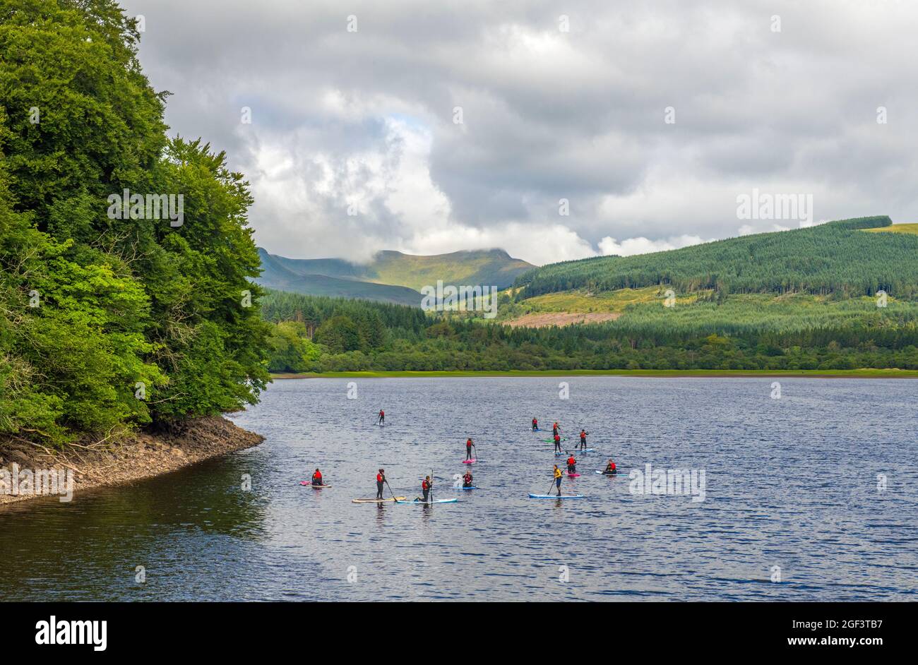 People learning to paddle board on Prntwyn Reservoir in the central Brecon Beacons Wales Stock Photo