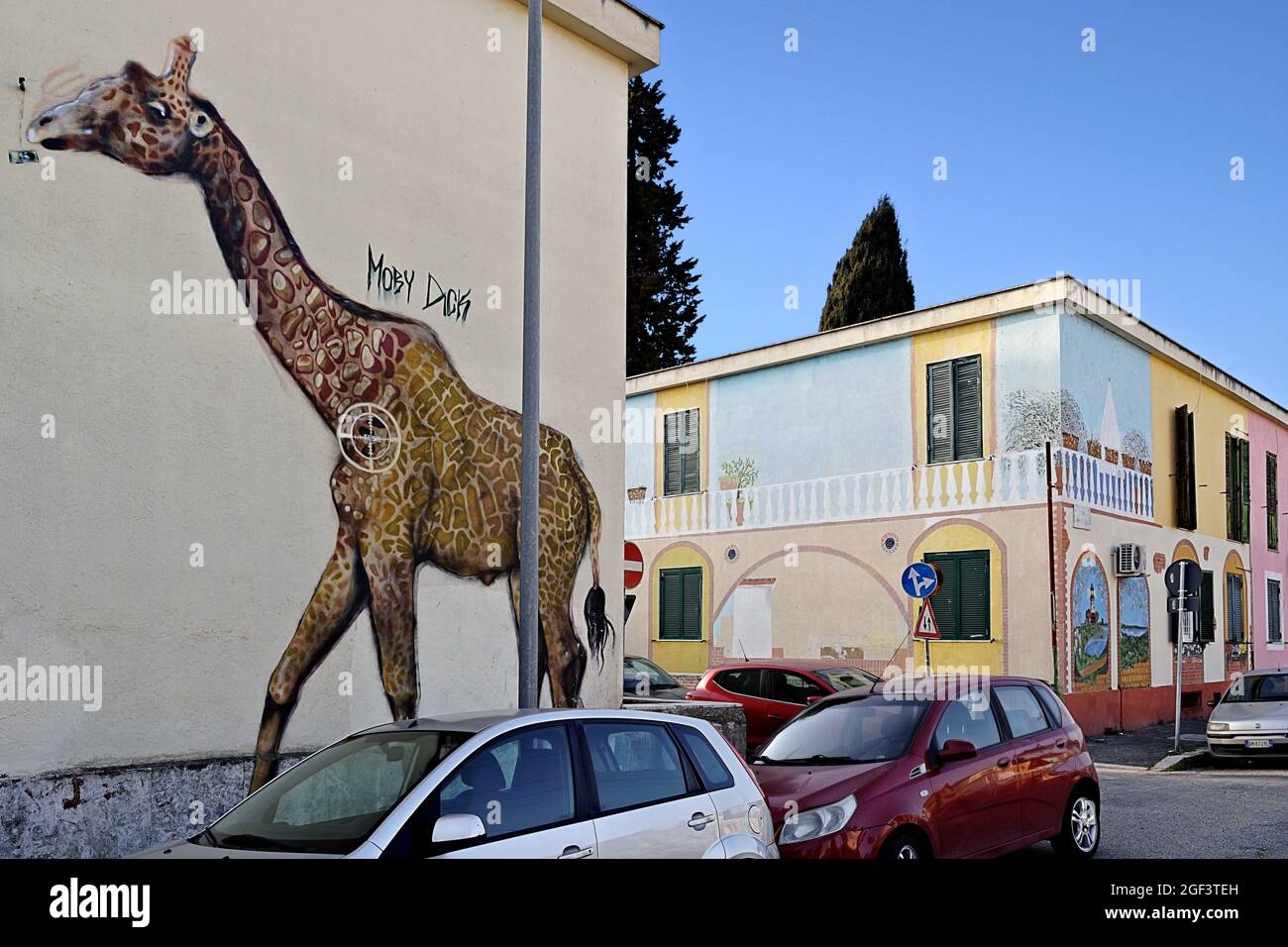 Glimpse of a street graffiti mural depicting a giraffe painted on a wall of a house in the Trullo district. Rome, Italy, Europe. Blue sky, copy space. Stock Photo