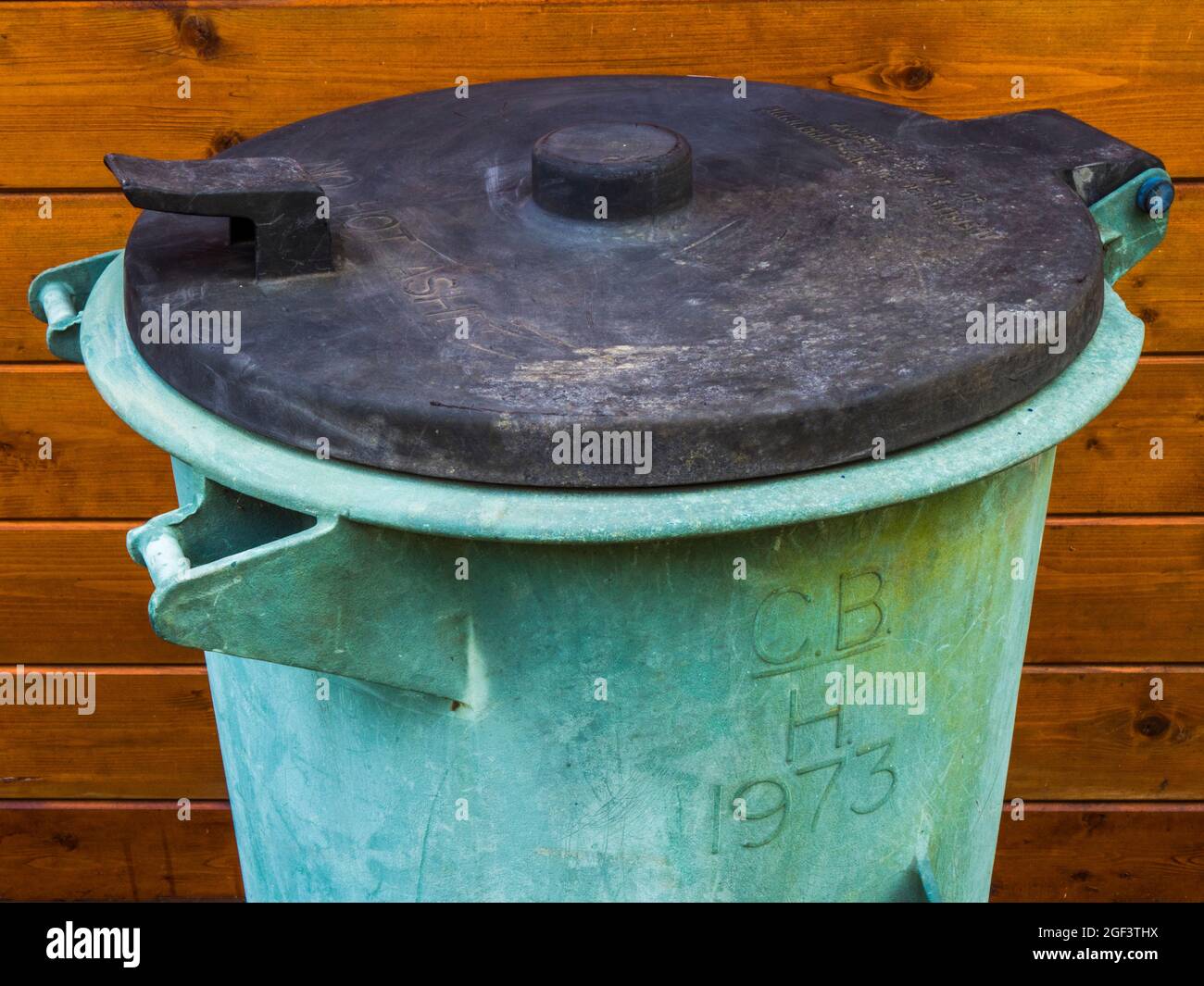 An old domestic household dustbin, with 1973 date on the side, and Property of City of Birmingham Salvage Department, in raised lettering on the lid. Stock Photo