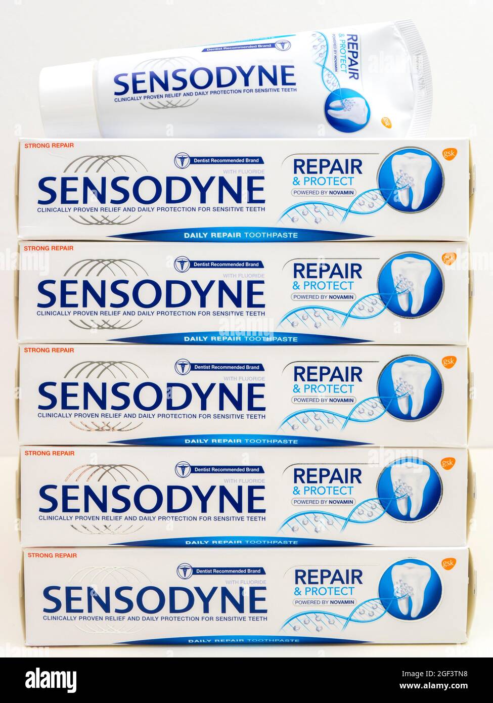 Closeup of five unopened boxes stacked vertically, with a fresh tube on top, of Sensodyne Repair & Protect toothpaste, formulated for sensitive teeth. Stock Photo