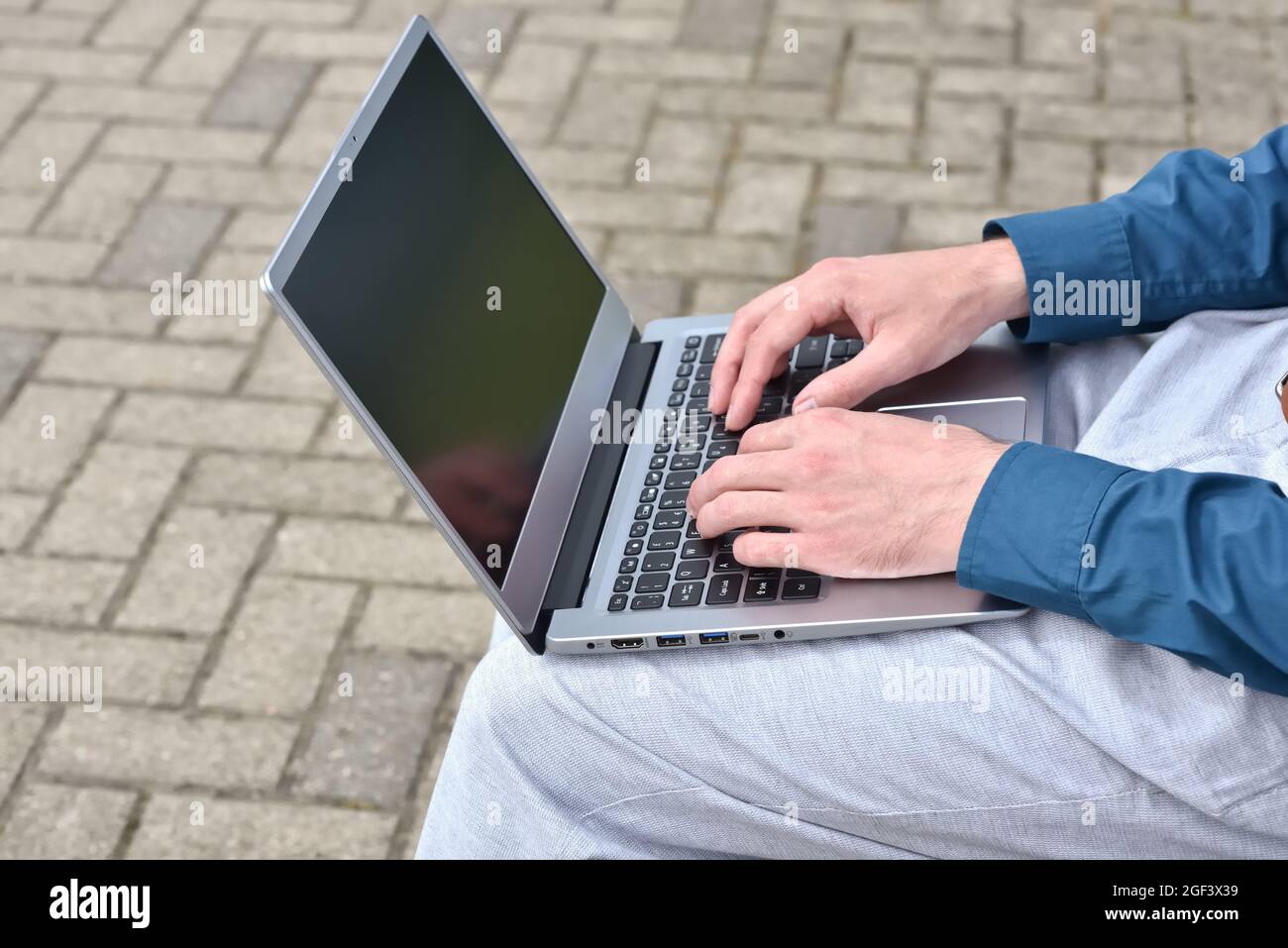 Laptop computer and man hands while working remotely on the computer outdoors.  Freelance programmer works remotely outdoors. Computer for learning Stock Photo