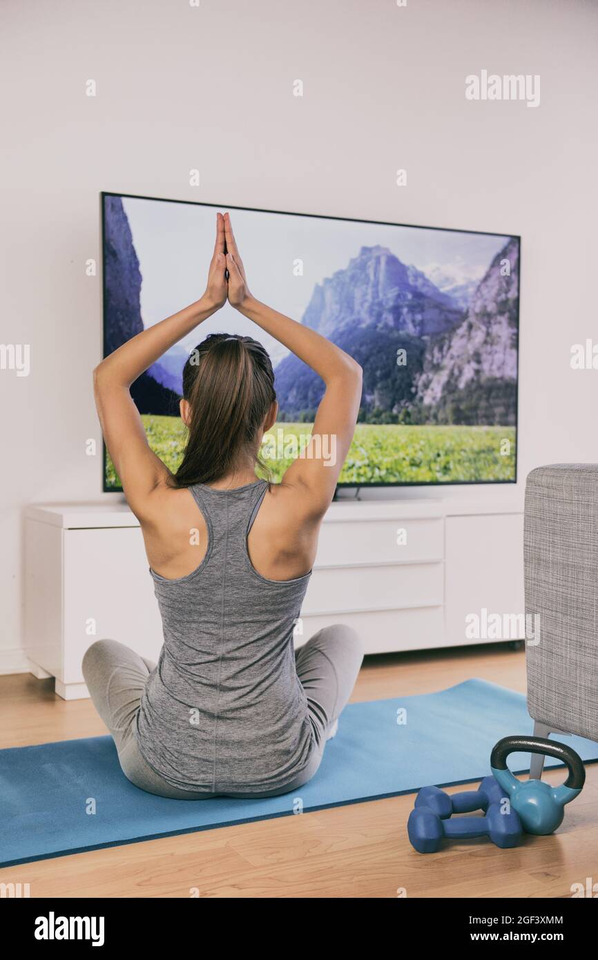 Yoga at home fitness class streaming on TV app online woman training in  living room on exercise mat meditating alone - workout lifestyle Stock  Photo - Alamy