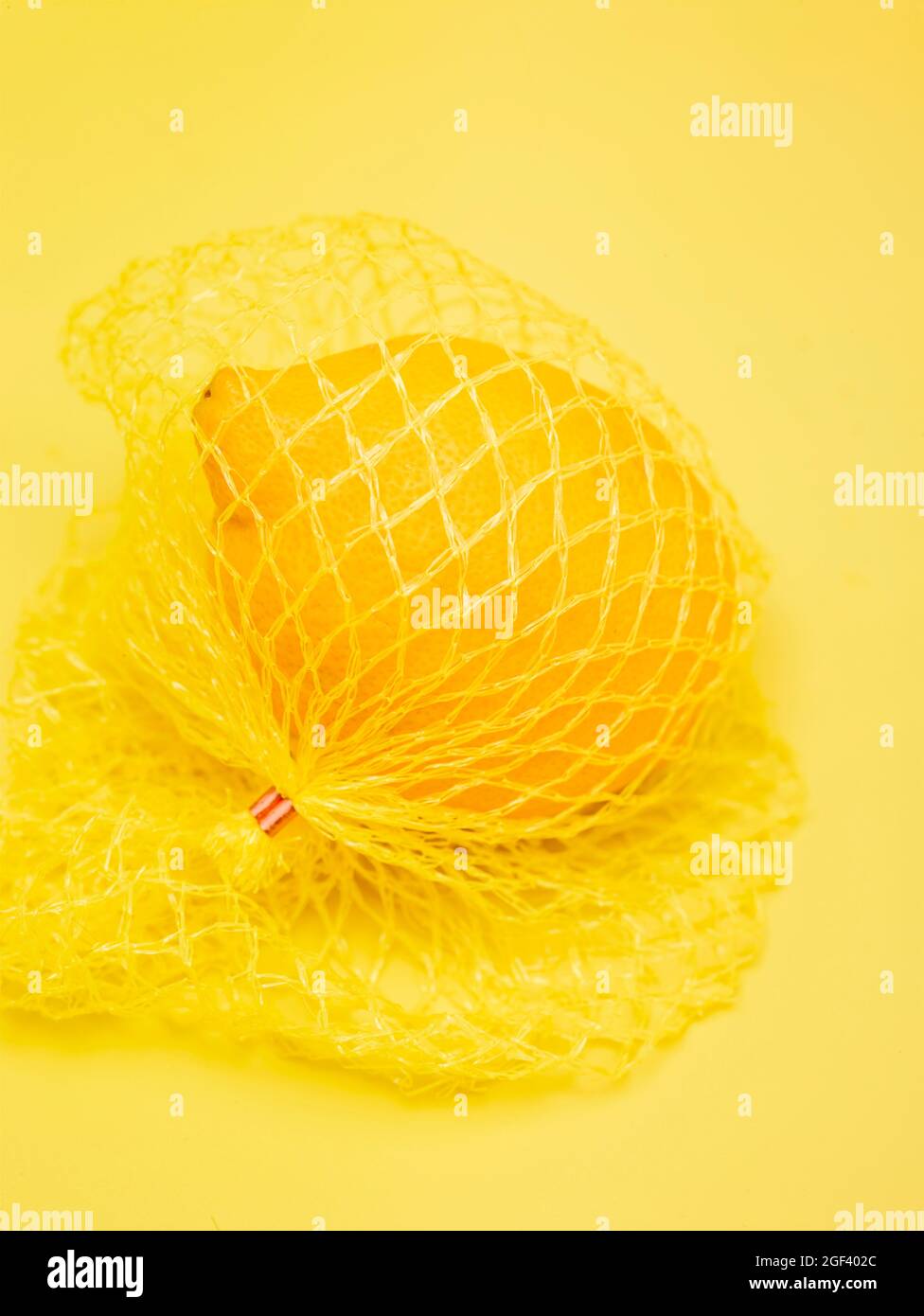 Lemon in string bag against yellow background in close-up. Food ...