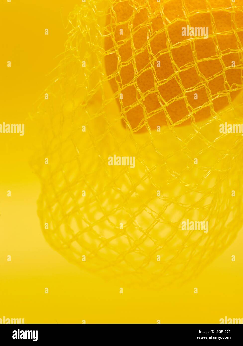 Lemon in string bag against yellow background in close-up. Food ...
