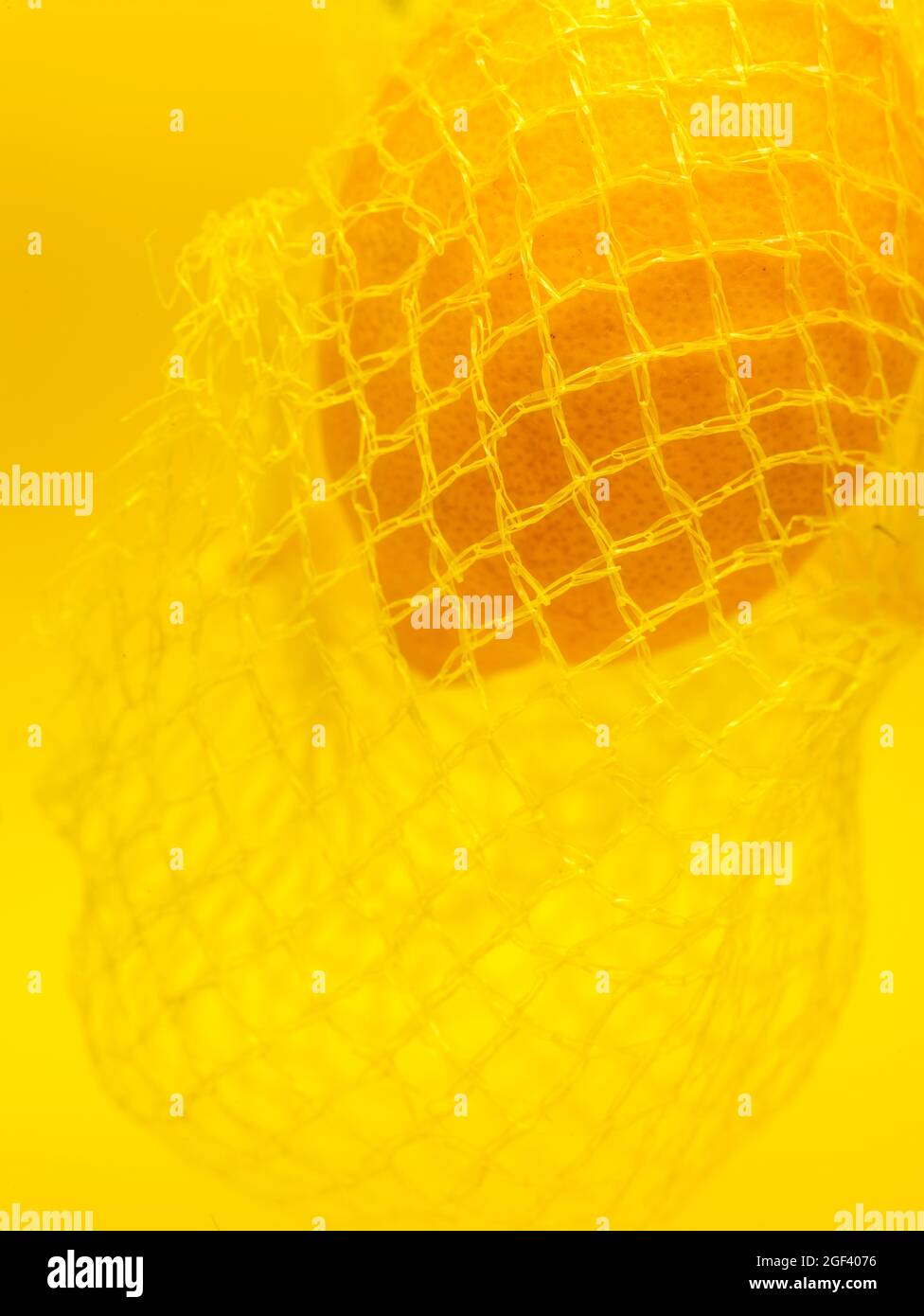Lemon in string bag against yellow background in close-up. Food ...