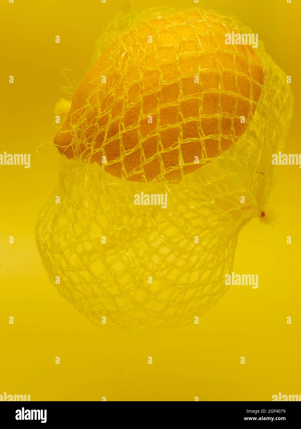 Lemon in string bag against yellow background in close-up. Food ...