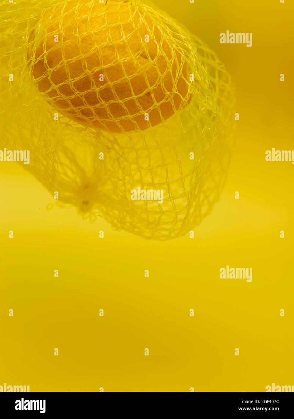 Lemon in string bag against yellow background in close-up. Food ...