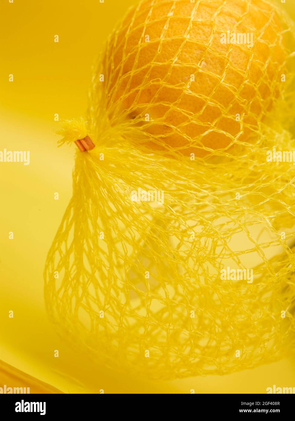 Lemon in string bag against yellow background in close-up. Food ...