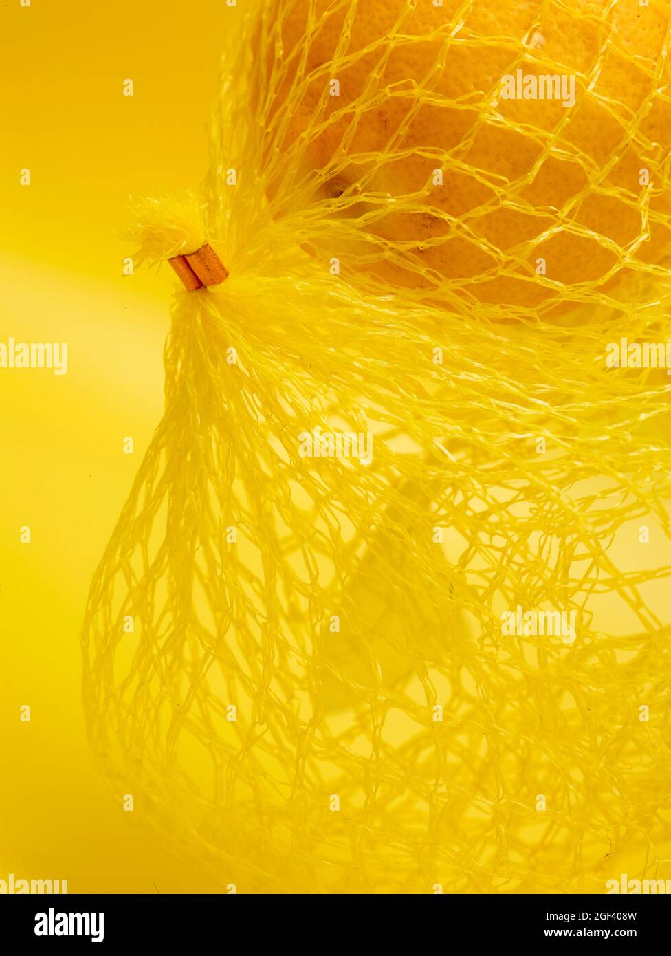 Lemon in string bag against yellow background in close-up. Food ...