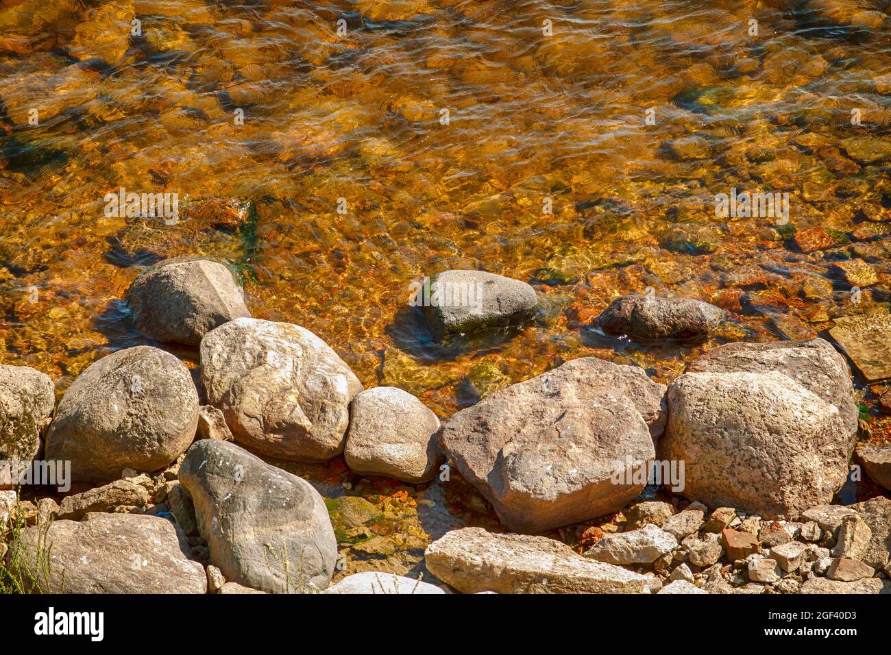 Small stones on the bank of the river with clear water Stock Photo - Alamy