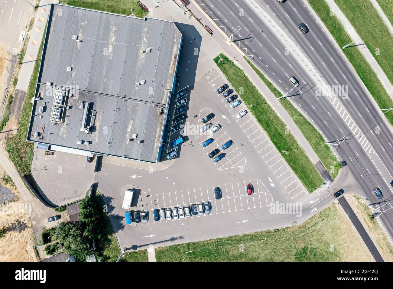 parking lot with rows of parked cars near shopping mall in sunny summer