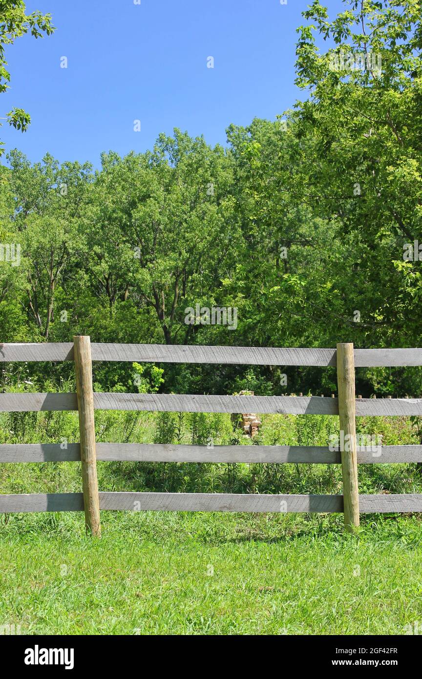 Traditional wooden boundary fence crossing a farm field on a bright ...