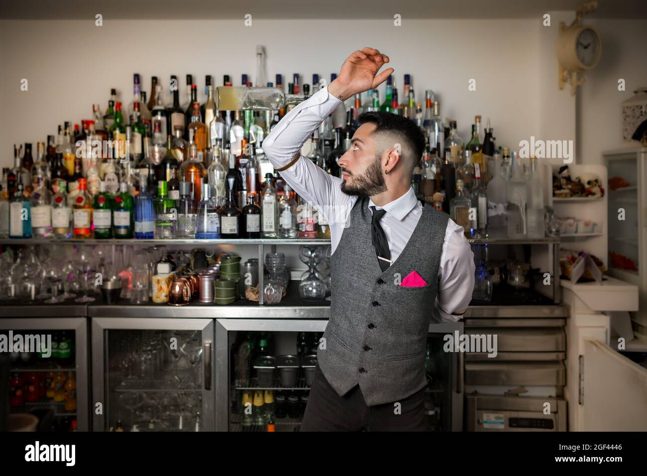 Skilled young bearded male bartender in stylish uniform performing trick  with bottle of alcoholic drink while preparing cocktail at bar counter  Stock Photo - Alamy