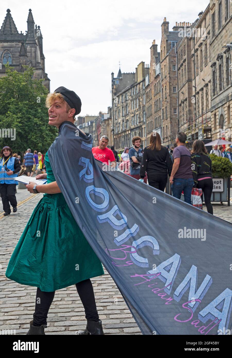 Edinburgh Royal Mile, Scotland, UK. 23 August 2021. Third and last full week of Edinburgh Fringe Festival which has been scaled back due to Covid-19 pandemic. Still reasonably busy but not as it would have been in previous years.Temperature 19 degrees for tourists  and residents out in the Scottish capital city centre. Pictured: Aiden Sadler promotes his show TROPICANA The Queer Comedy Cabaret at Jenner Theatre. Credit: Arch White/Alamy Live News. Stock Photo