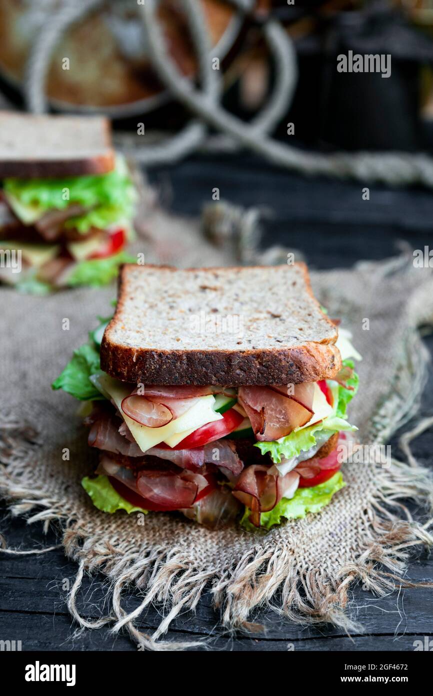 Big sandwich with bread, prosciutto, lettuce, tomtatoes, cucumber and