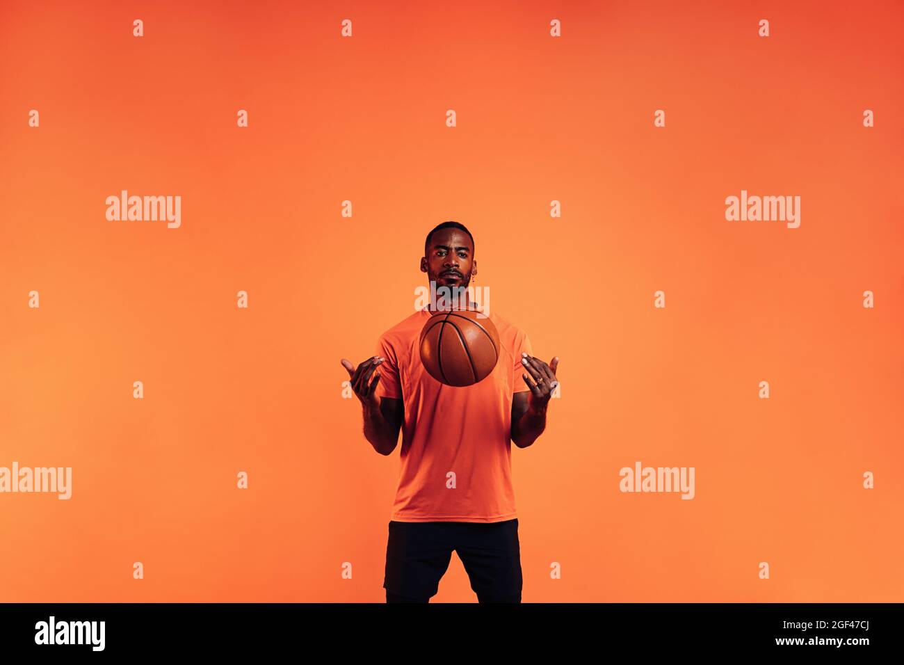 Serious guy in sportswear throws a basketball in front of him in the