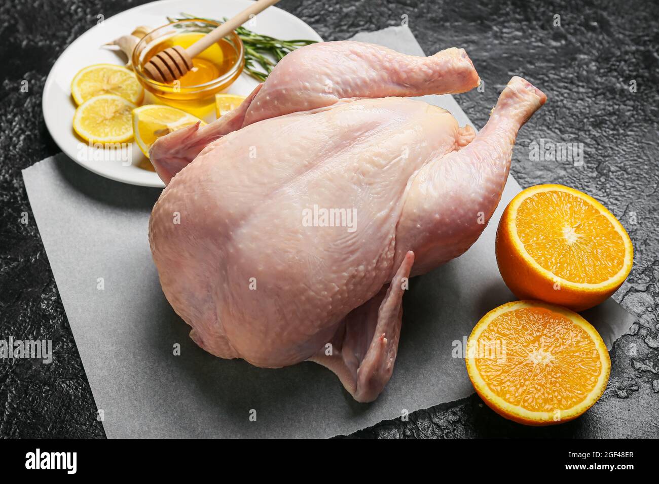 https://c8.alamy.com/comp/2GF48ER/parchment-with-whole-raw-chicken-orange-lemon-and-spices-on-dark-background-closeup-2GF48ER.jpg