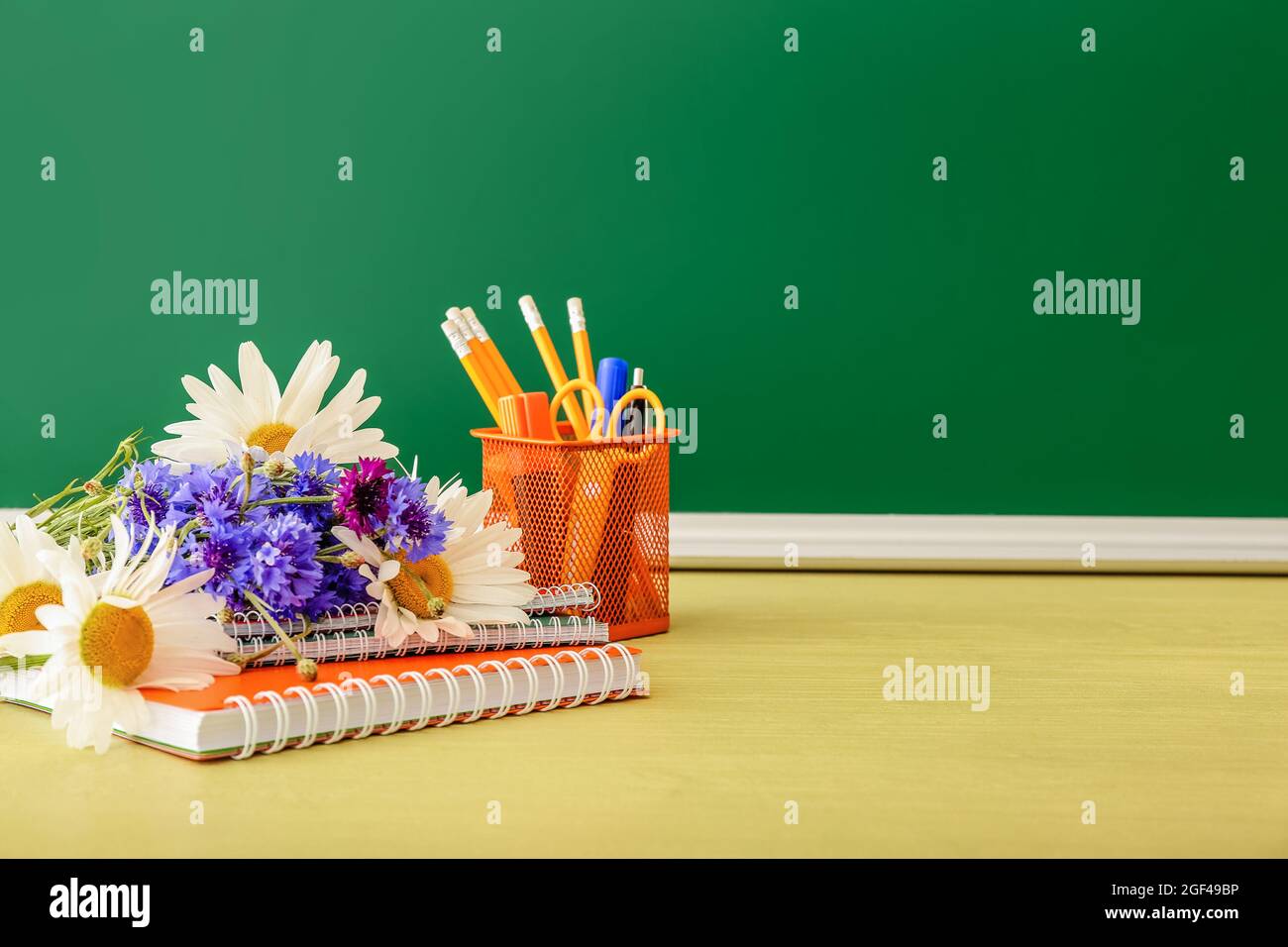 Beautiful flowers and stationery on table in classroom. Teacher's Day celebration Stock Photo