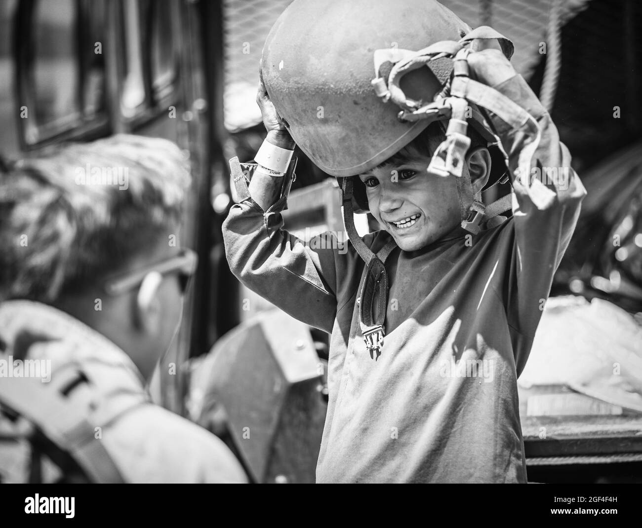 A U.S. Marine assigned to Special Purpose Marine Air-Ground Task Force – Crisis Response – Central Command hands a helmet to a child awaiting evacuation at Hamid Karzai International Airport, Afghanistan, Aug. 22, 2021. The U.S. is assisting the Department of State with a Non-Combatant Evacuation Operation (NEO) in Afghanistan. (U.S. Marine Corps photo by Gunnery Sgt. Melissa Marnellvia American PhotoArchive/Alamy) Stock Photo