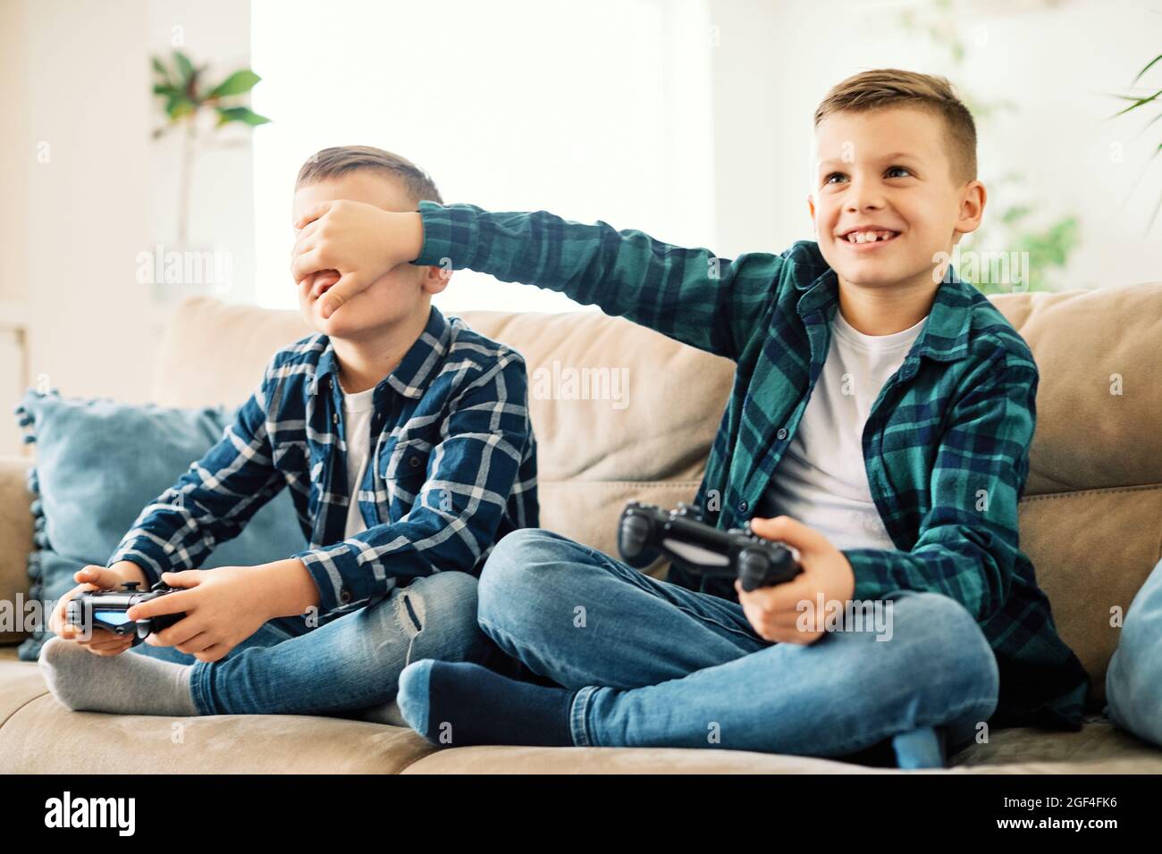 child brother friend having fun playing console laughing happy kid controller gaming Stock Photo
