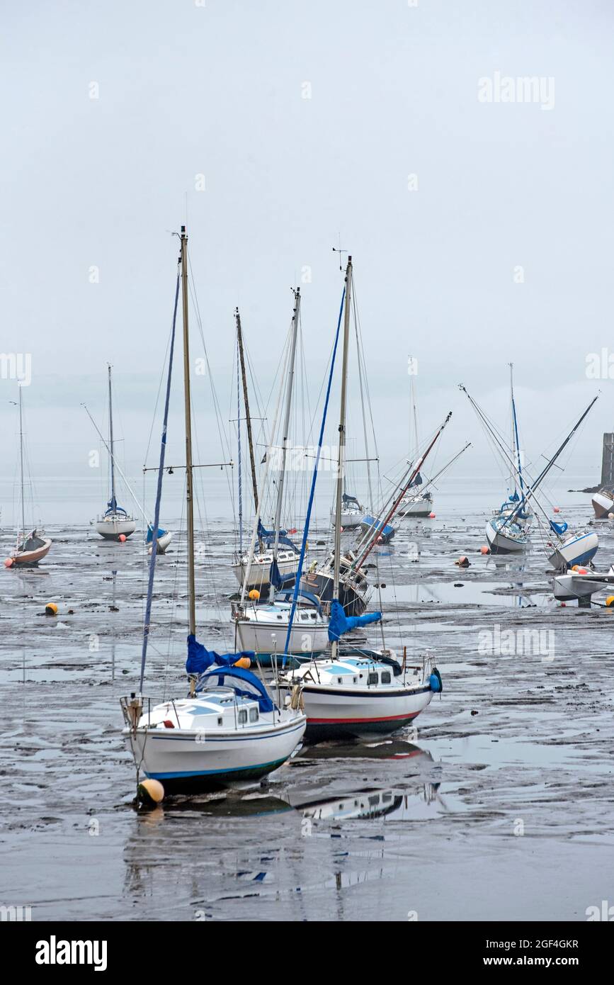 Small boats resting in the mud at low tide in Granton Harbour on the Firth of Forth, Edinburgh, Scotland, UK. Stock Photo