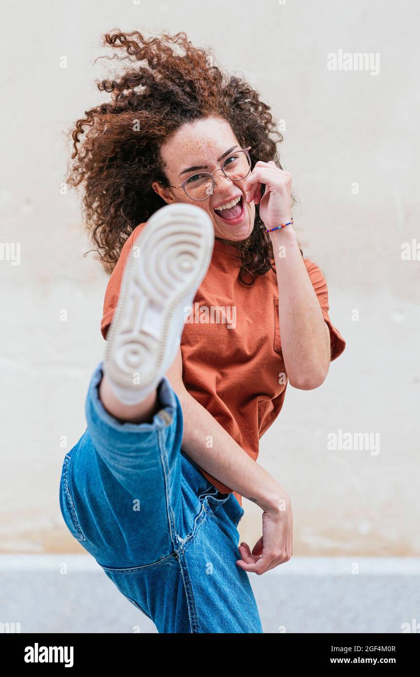 Excited young woman kicking in front of wall Stock Photo Alamy