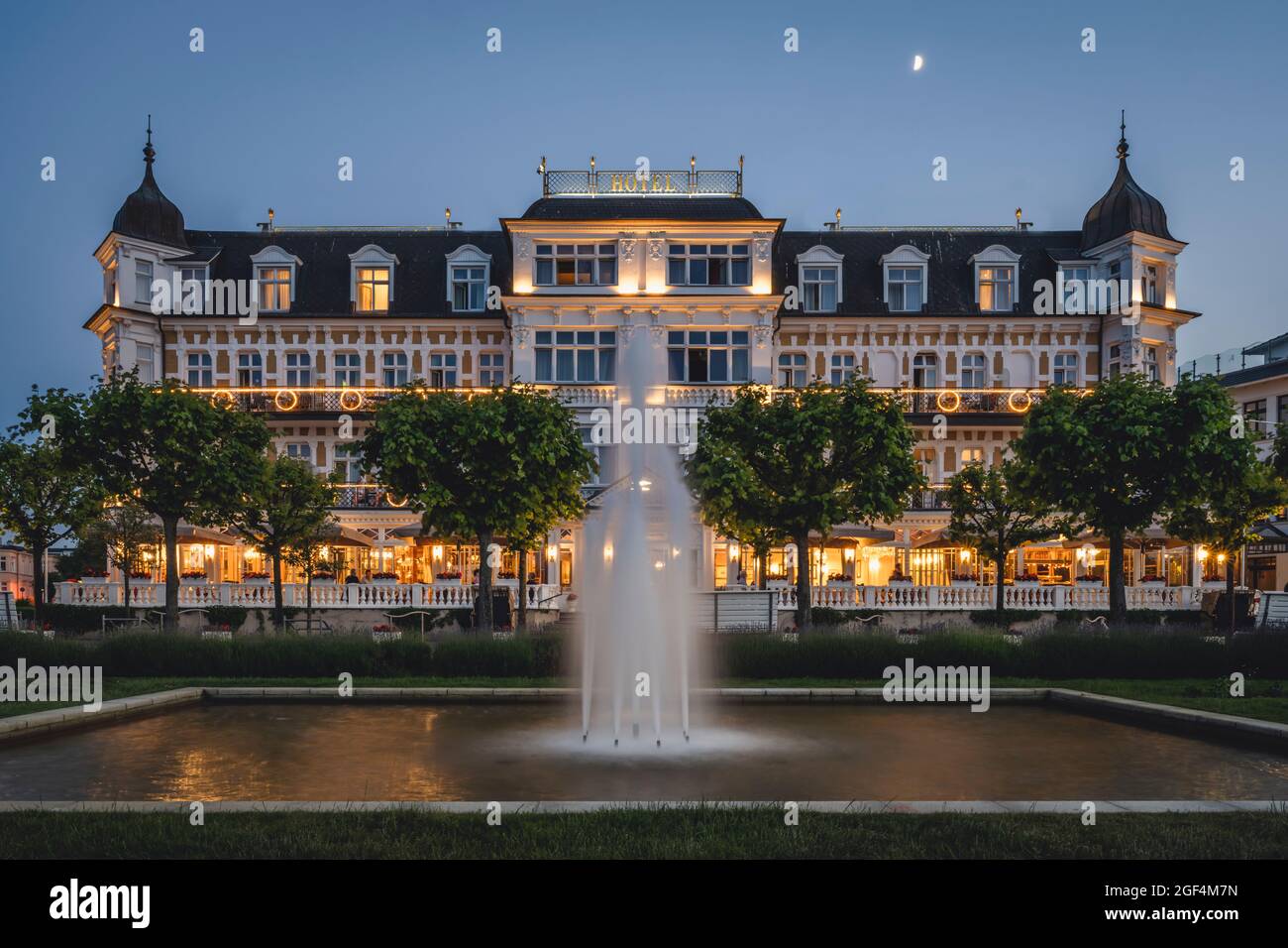 Germany, Mecklenburg-Western Pomerania, Heringsdorf, Fountain splashing in front of luxury hotel at dusk Stock Photo