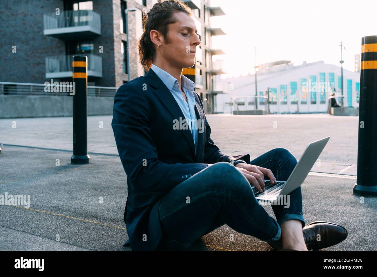 Businessman using laptop while sitting cross-legged on footpath Stock Photo