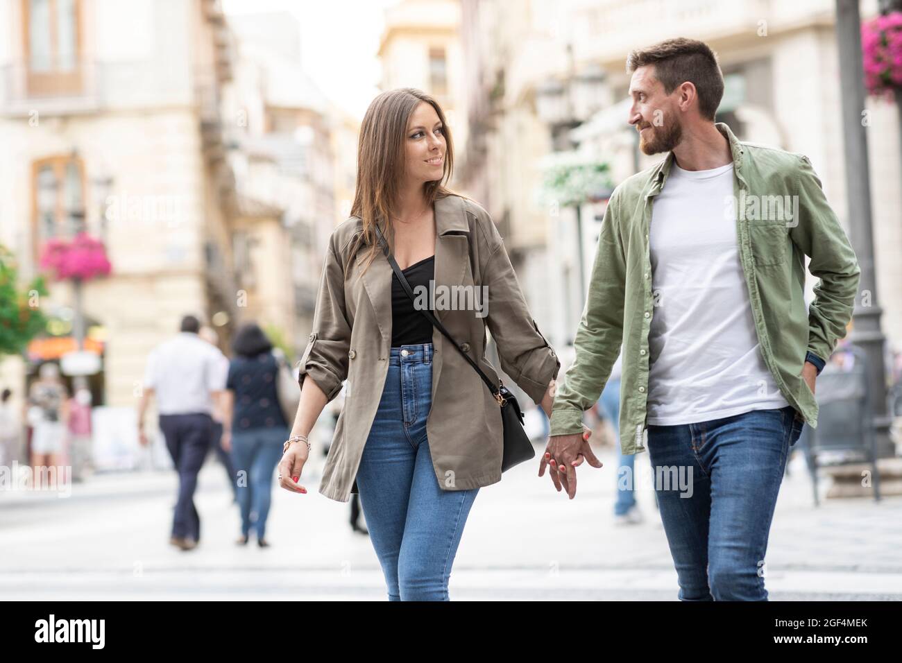 Couple holding hands while walking on city street Stock Photo - Alamy