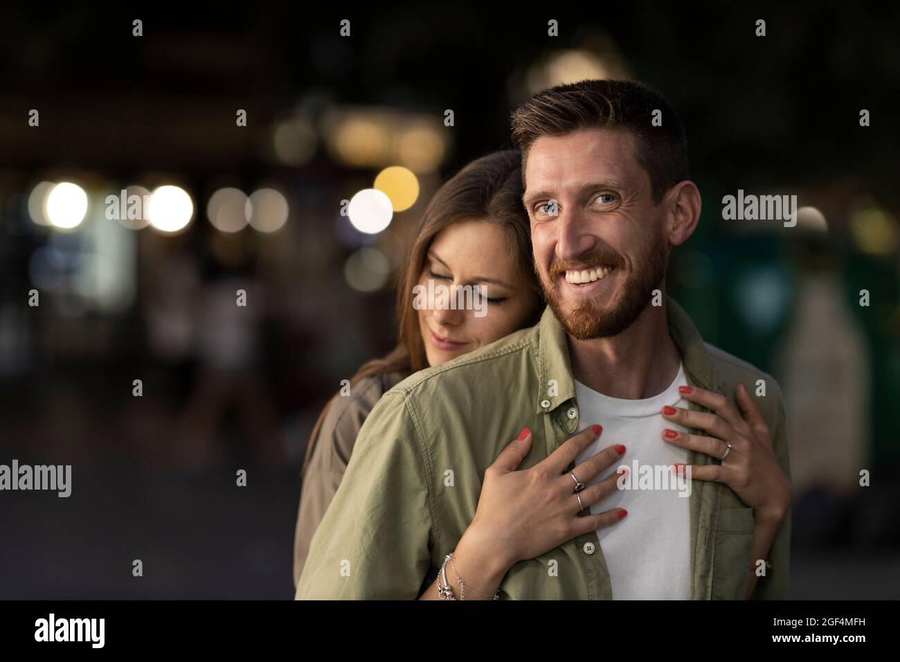 Woman embracing smiling boyfriend from behind Stock Photo