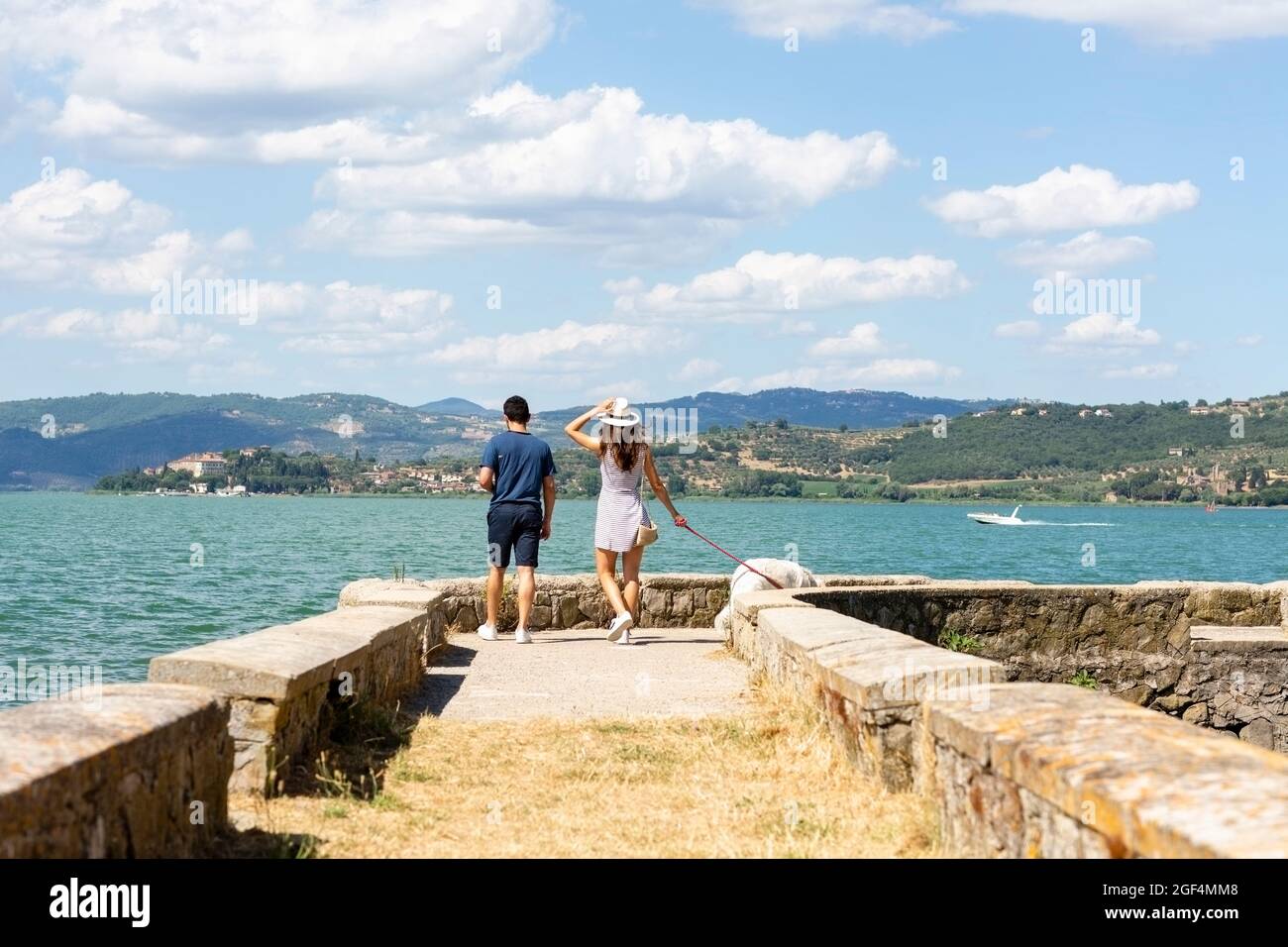 Tourist couple walking with dog on pier Stock Photo