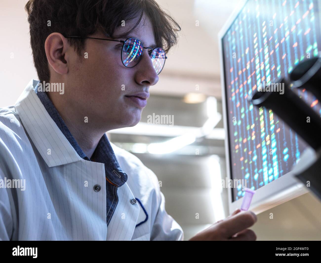 Male scientist with DNA sample examining test results in laboratory Stock Photo