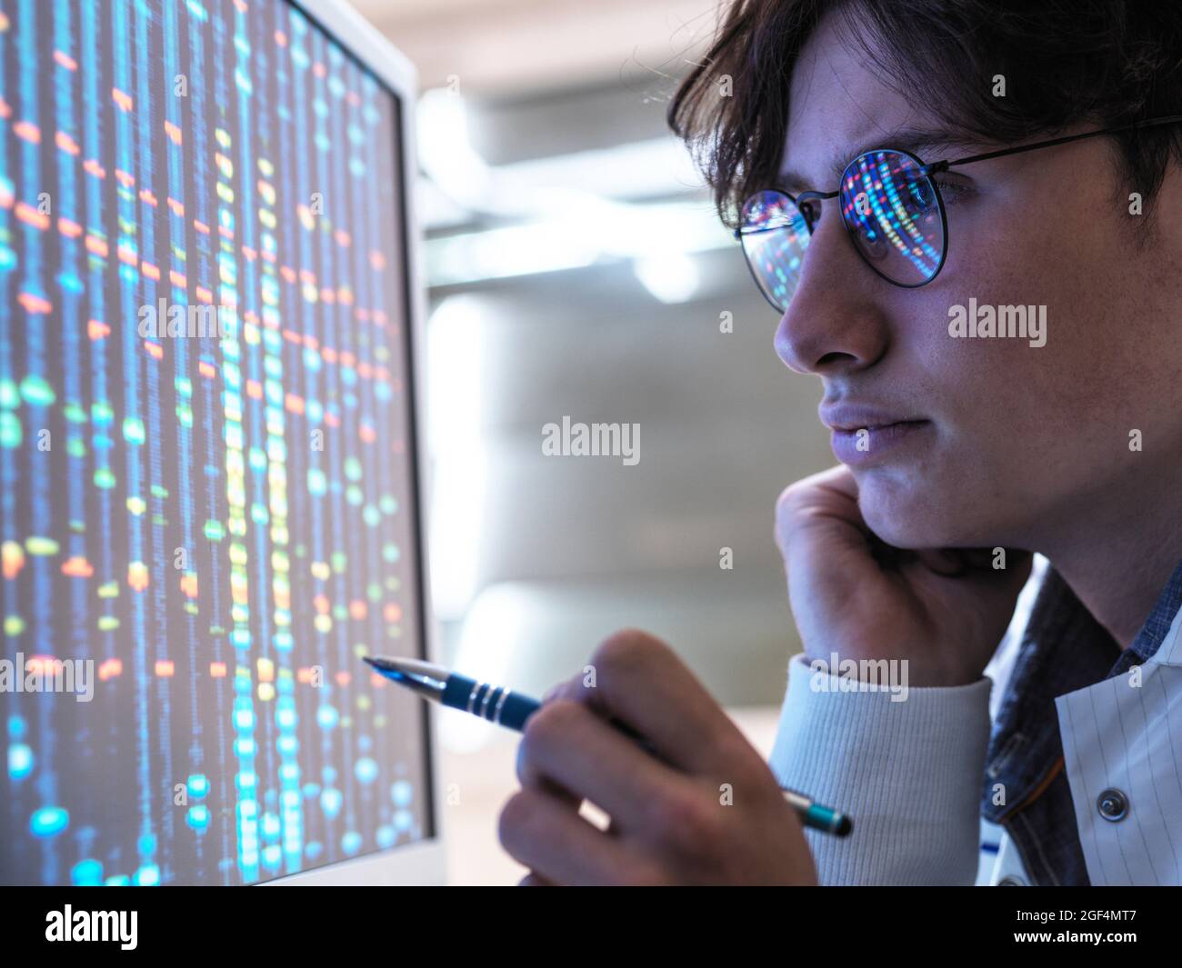Male teenage expert analyzing DNA through computer at laboratory Stock Photo